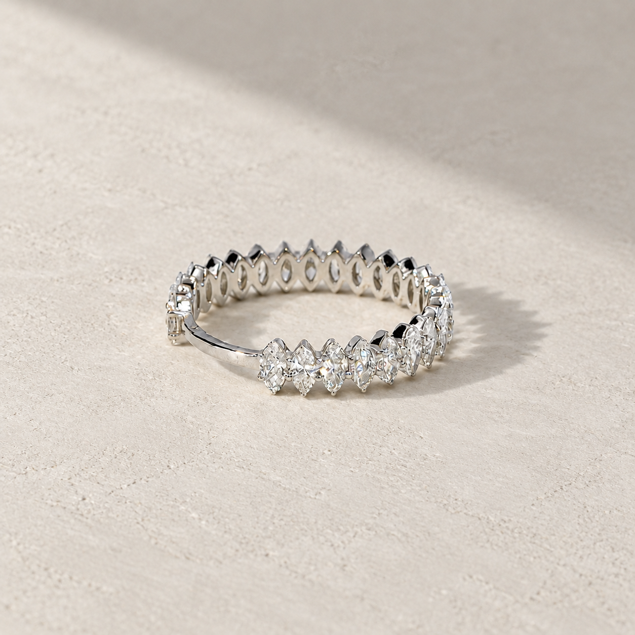 marquise diamond half eternity band in 14K white gold, set with lab-grown diamonds, photographed on a light grey-beige background with natural shadows.