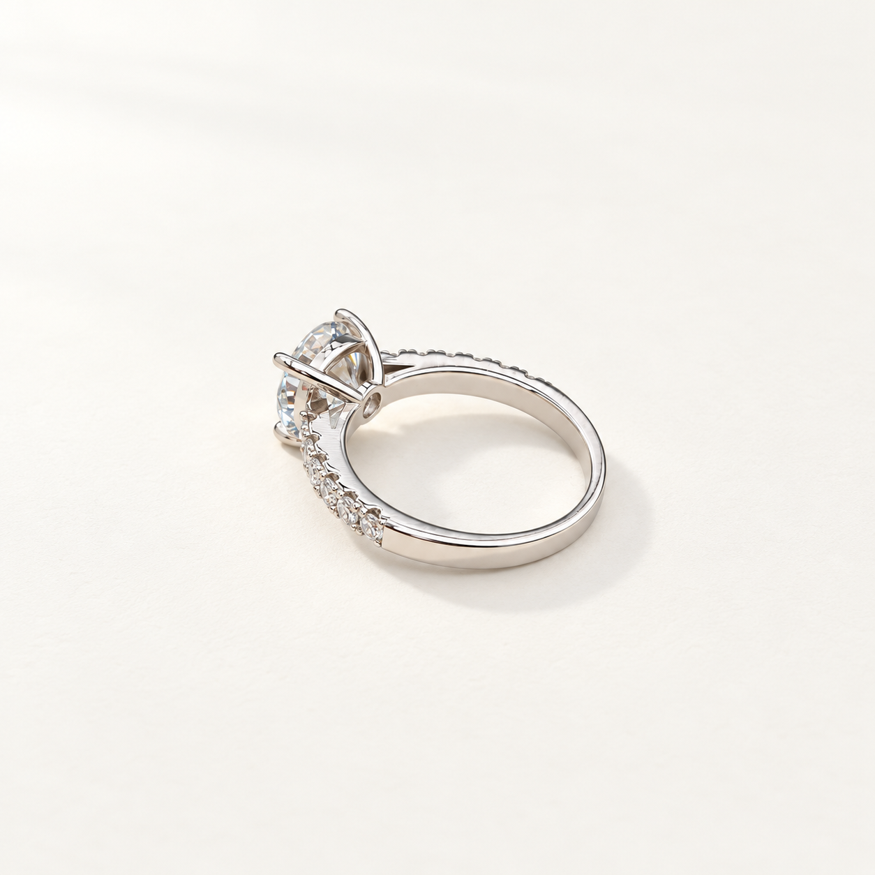 A silver-toned diamond ring with a large round center moissanite stone and a pavé band, photographed on a clean white background.